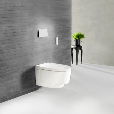 Een grijze betonwand met een grove, natuurlijke structuur geeft uw badkamer een uniek tintje. Het witte keramiek van Geberit AquaClean Mera past hier perfect bij en sluit mooi aan op deze robuuste uitstraling.