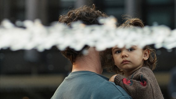 Meisje op de arm van haar vader, met een waterstraal op de voorgrond.