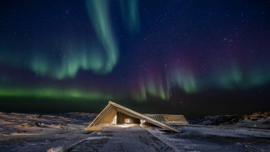 Het ijsfjordencentrum in het spectaculaire noorderlicht van de Groenlandse poolnacht (© Adam Mørk)