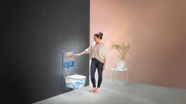 Vrouw bedient de spoeling van het Geberit WC-systeem (© Geberit)