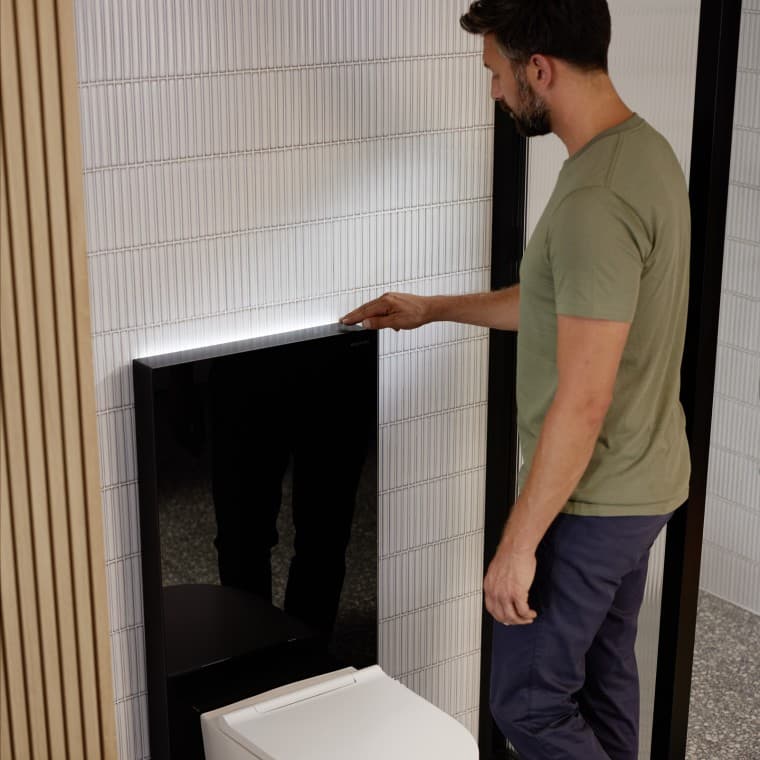 Man naast een Geberit Monolith Plus sanitairmodule Man naast een Geberit Monolith Plus sanitairmodule