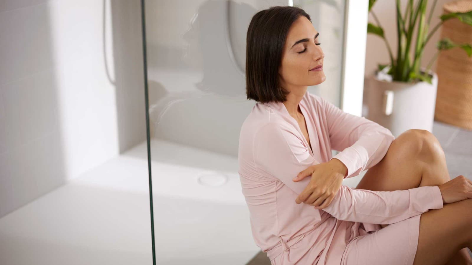 Vrouw zittend in de badkamer, voor de douche Vrouw zittend in de badkamer, voor de douche